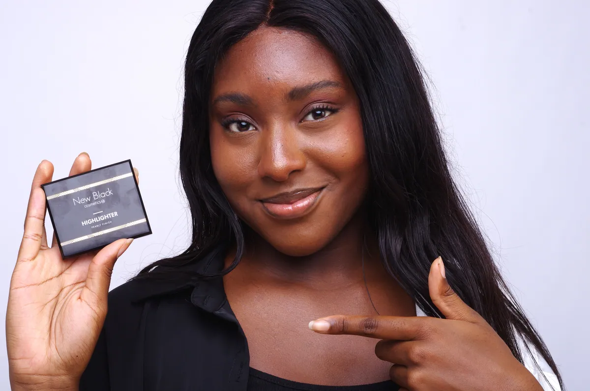 Yeux marron sur peau noire avec un trait fin et une touche de highlighter doré